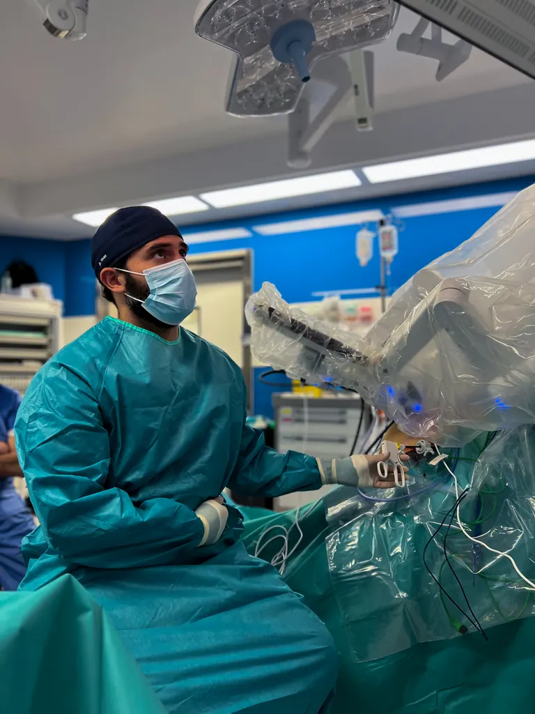 Profesional del equipo quirúrgico junto al paciente y los brazos del sistema de cirugía robótica