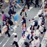 Mujer joven entre una multitud de peatones en un paso de cebra