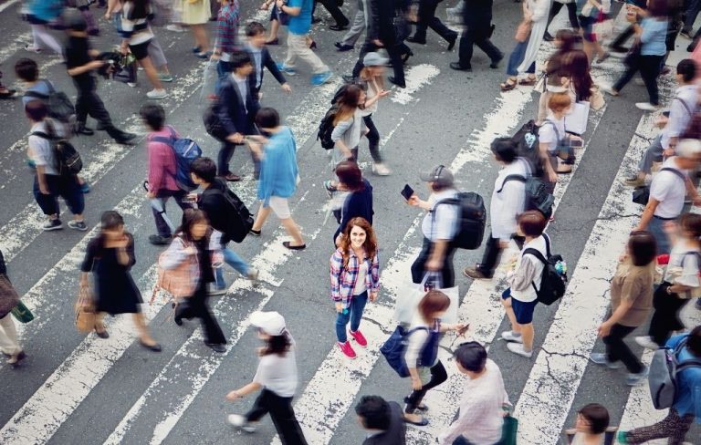 Mujer joven entre una multitud de peatones en un paso de cebra