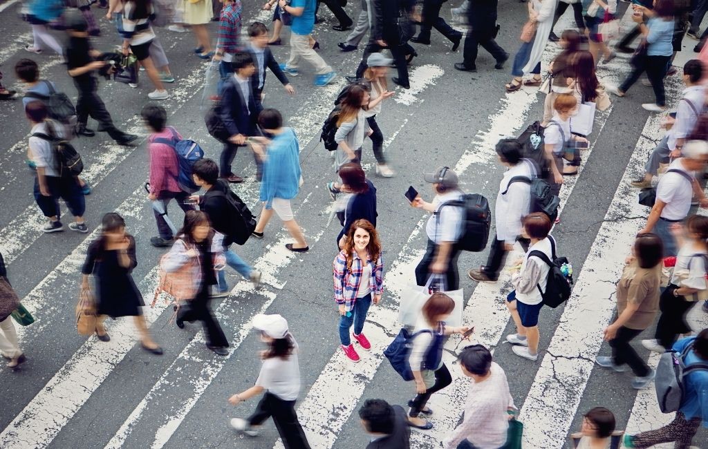 Mujer joven entre una multitud de peatones en un paso de cebra